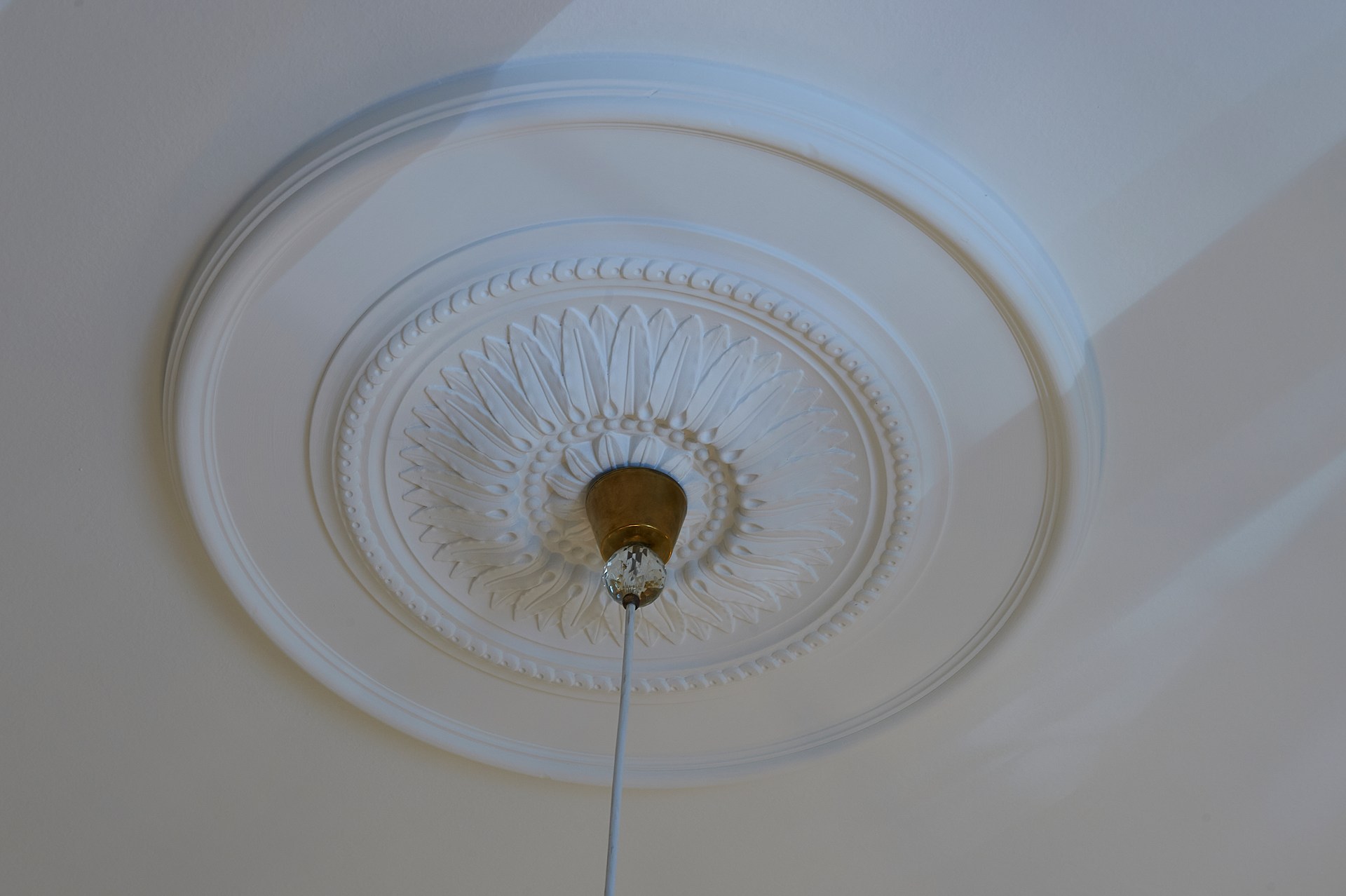 Decoratieve rozet met gedetailleerd reliëf, laat een hanglamp in een elegant plafondontwerp extra uitkomen.
