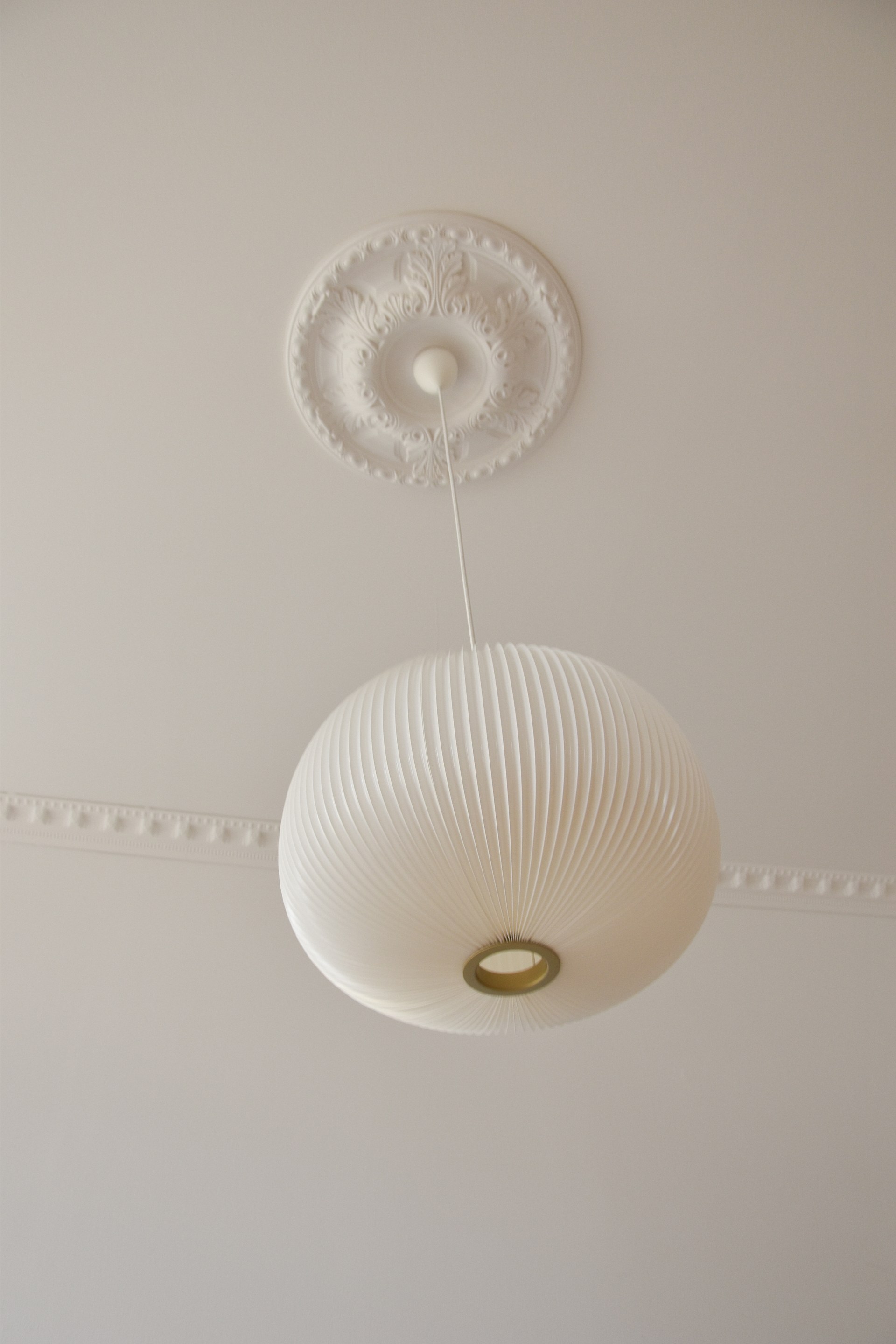Een versierde plafondrozet omlijst een hanglamp voor een elegante plafonddecoratie.