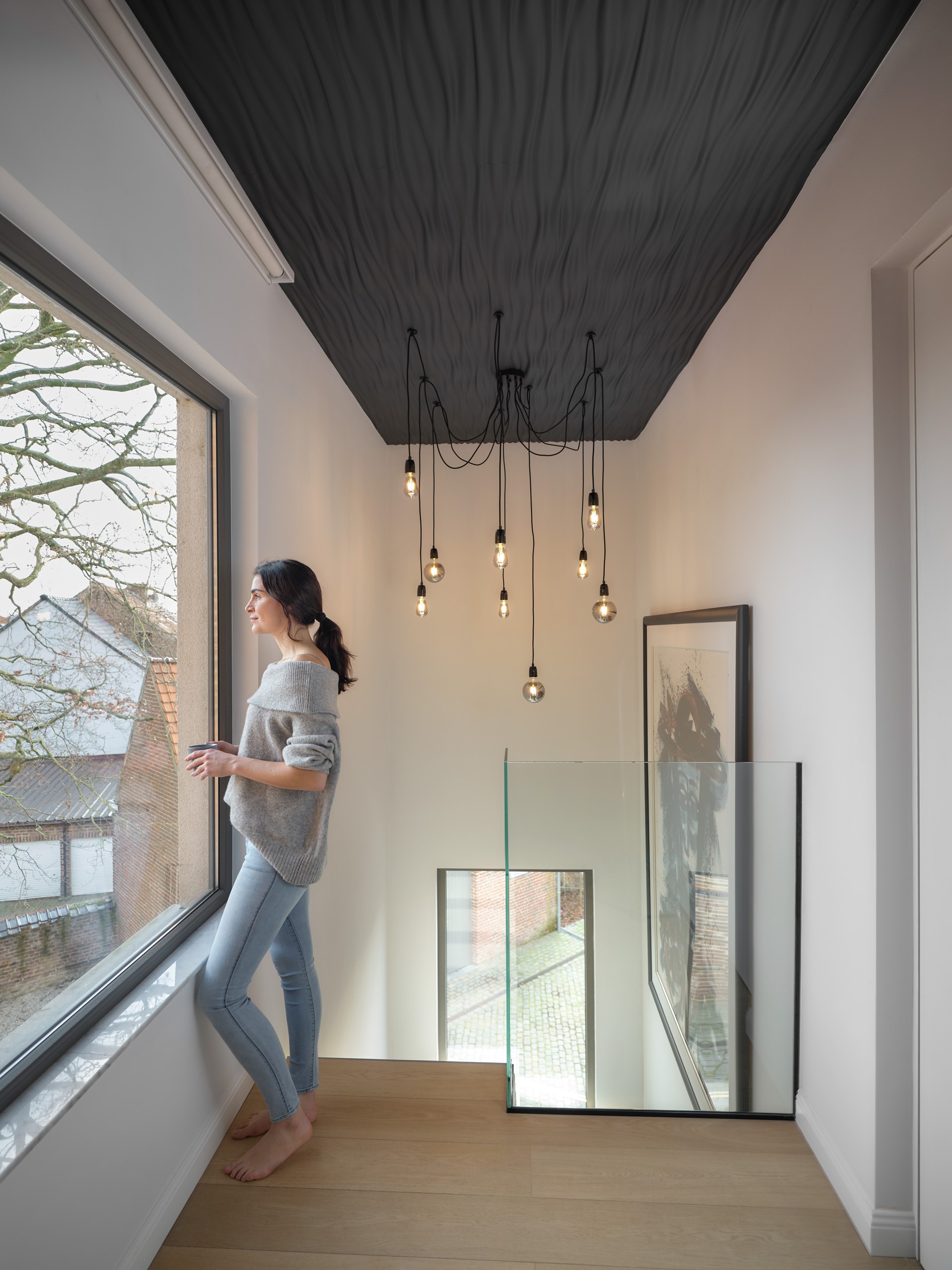 Wandpanelen met structuur zijn aan het plafond aangebracht, waardoor een sculpturaal plafondelement met een sterke visuele diepte is ontstaan.