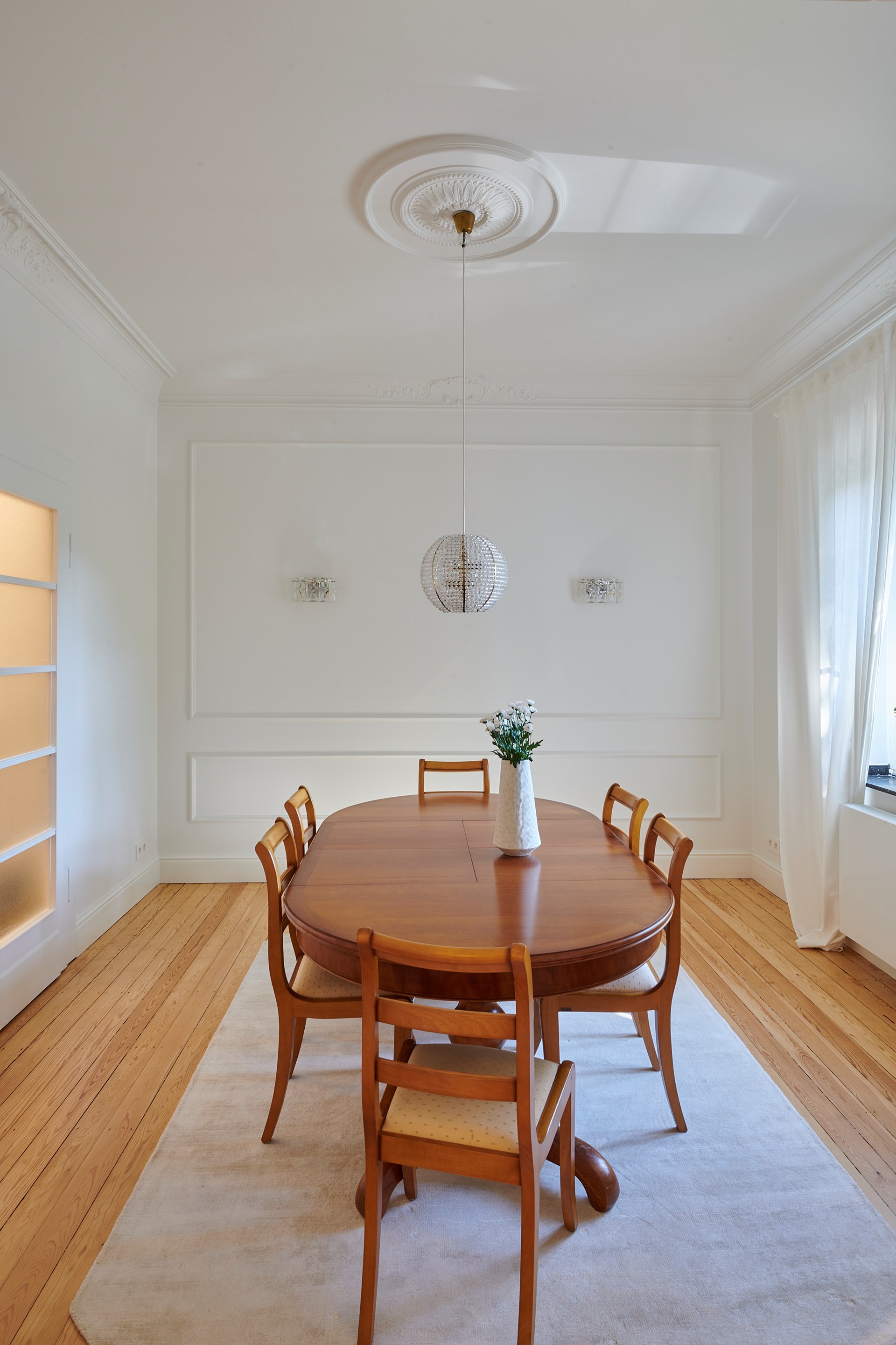 Een decoratieve plafondrozet en sierlijsten die een verfijnde eetkamer met hanglampen nog meer opwaarden.