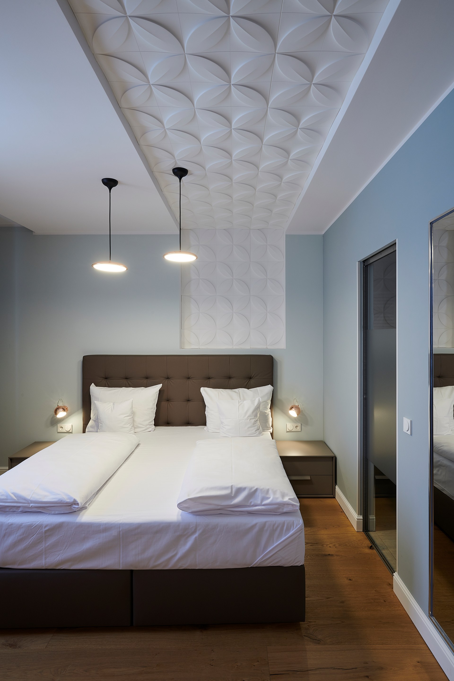 Decoratieve wandpanelen zijn aan het plafond bevestigd, waardoor boven het bed een plafond met structuur is ontstaan.